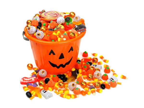 Halloween Jack o Lantern candy pail overflowing with sweets over white