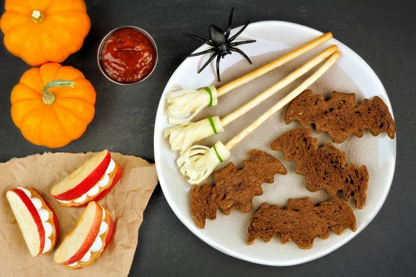 Pane di pipistrello di Halloween, manici di scopa e denti di mela mostro, in testa su ardesia — Foto Stock