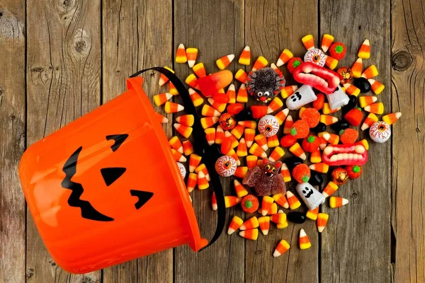 Halloween Jack o Lanterna balde com derramamento de doces, vista acima sobre a madeira — Fotografia de Stock