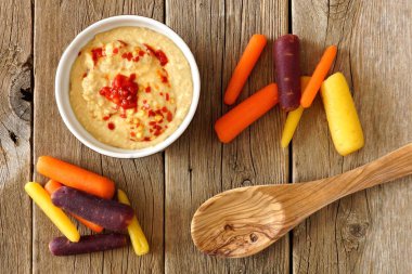 Bebek gökkuşağı havuç Humus ile daldırma, ek yükü bir rustik ahşap üzerine