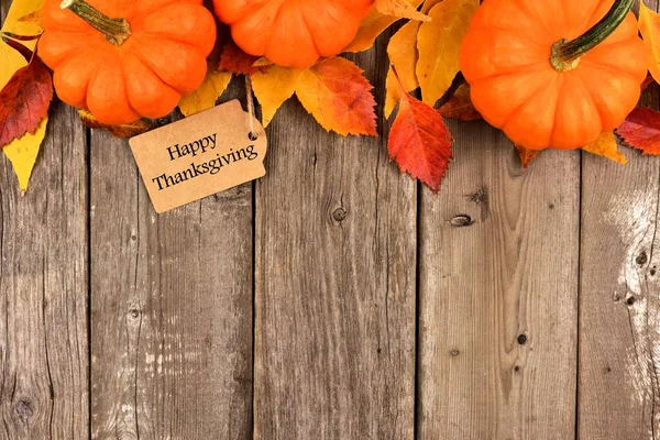 Mutlu Şükran günü etiketi ile üst kenarını kabaklar ve tahta üzerinde yapraklar