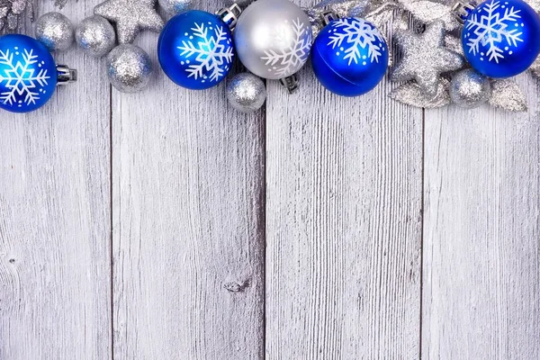Blue and silver Christmas ornament top border on white wood