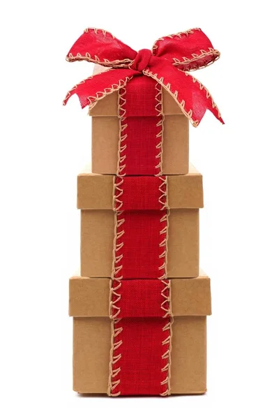 Caixas de presente marrom empilhadas com arco vermelho e fita isolada em branco — Fotografia de Stock