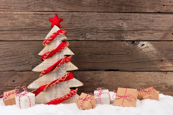 Árbol de Navidad de madera con guirnalda roja rústica en la nieve —  Fotos de Stock