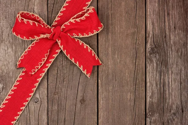 Arco de Natal vermelho e borda de canto de fita em madeira velha — Fotografia de Stock