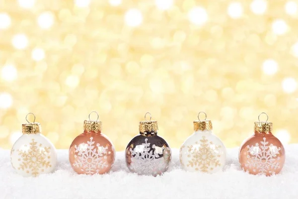 White and gold Christmas ornaments in snow