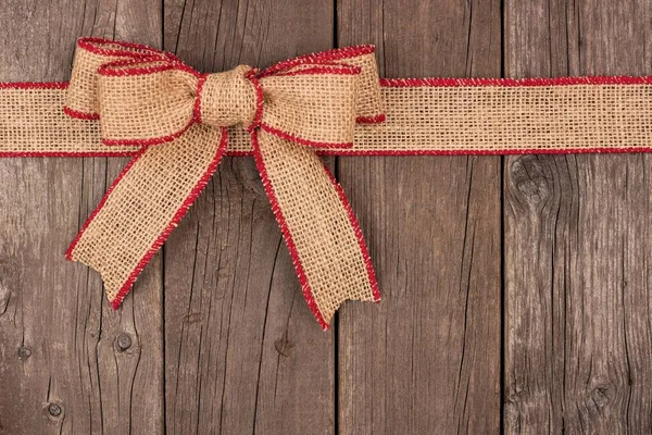 Burlap Christmas bow and ribbon top border on wood — Stock Photo, Image