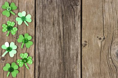 El yapımı kağıt yoncaları rustik ahşap arka plan üzerinde St Patricks Günü yan sınır