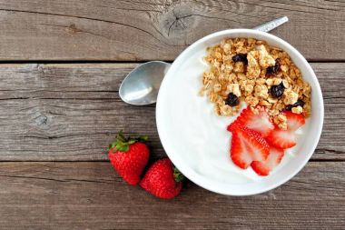 Kase yoğurt çilek ve granola rustik ahşap arka plan üzerinde. Düz yatıyordu.