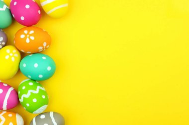 Sarı kağıt arka plan üzerinde renkli Paskalya yortusu yumurta yan sınır