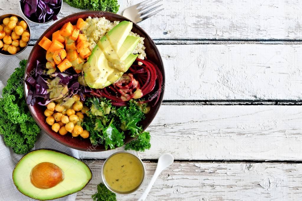 Buddha bowl with quinoa, avocado, chickpeas, vegetables on a white wood background, Healthy food concept. Top view, side border with copy space.