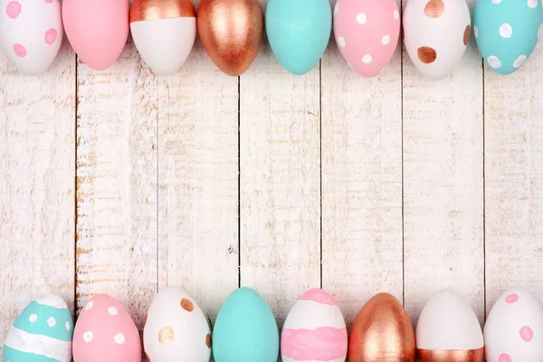 Easter egg double border. Rose gold, pink, turquoise and white colors on a white wood background.