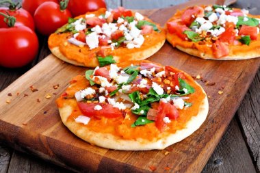 Baharatlı humus mini düz ekmek domates ve beyaz peynir ile. Tahta arka plan ile kürek gemide kapatın. Sağlıklı beslenme kavramı.