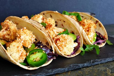 Kavrulmuş Hindistan cevizi karnabahar Taco. Sağlıklı, vegan yemek. Yakın çekim, karanlık bir arka plan üzerinde görünümü yan.