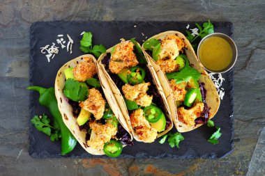 Kavrulmuş Hindistan cevizi karnabahar Taco. Sağlıklı, vegan yemek. Karanlık kayrak taş zemin üzerine görünümünün üst.