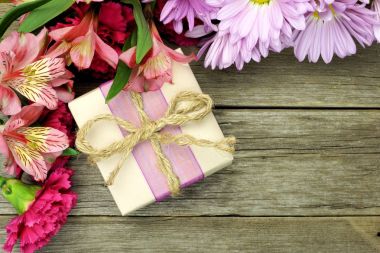 Çiçek ahşap arka plan üzerinde köşe kenarlıklı rustik hediye kutusu