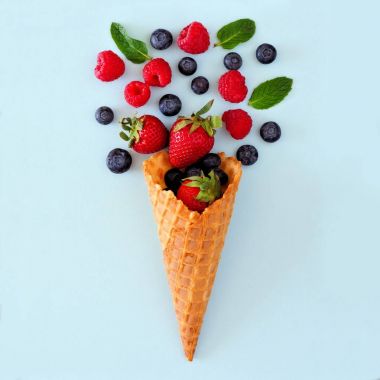 Berry meyve gözleme dondurma koni çeşitli. Düz yatıyordu kavram pastel mavi bir arka plan üzerinde.