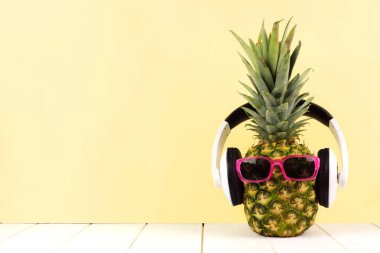 Güneş gözlüğü ve sarı bir arka plan karşı kulaklık ile hippi ananas. En az yaz konsepti.