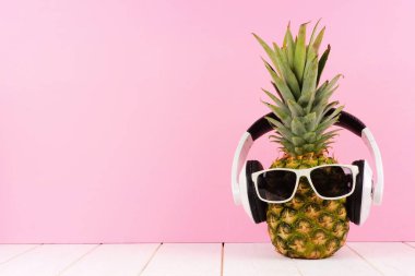 Güneş gözlüğü ve pembe bir arka plan karşı kulaklık ile hippi ananas. En az yaz konsepti.