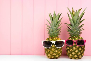 Pembe ahşap arka plan karşı trendy güneş gözlüğü ile hipster ananas. En az yaz konsepti.