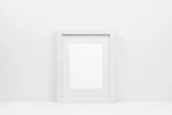Mock up white frame on a shelf or desk. White color scheme. Portrait frame orientation.