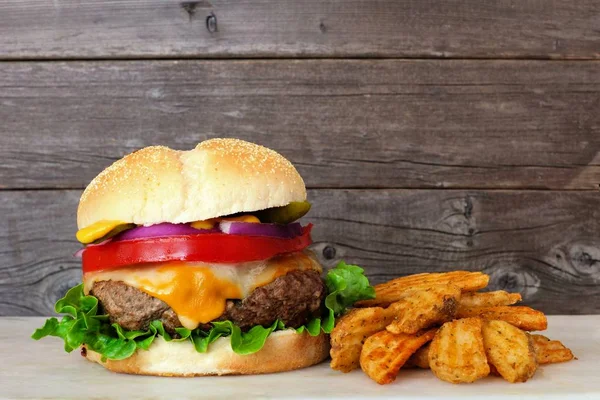 Traditional hamburger with potato wedges against a rustic wood background