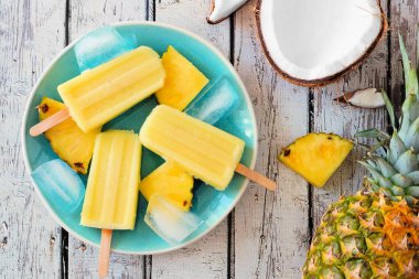 Bir tabağa ananas Hindistan cevizi buz açılır. Bir beyaz tahta arka plan sahnesine Üstten Görünüm.