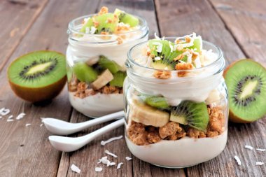 Sağlıklı kivi, muz, Hindistan cevizi gezegendeki mason kavanoz rustik ahşap arka plan üzerinde