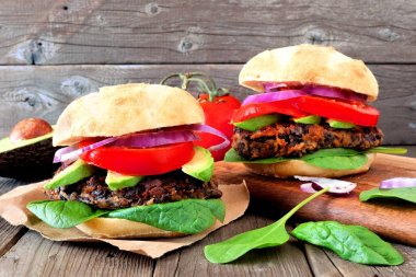 İki vejetaryen bakla ve tatlı patates hamburger avokado ve ıspanak bir rustik ahşap arka plan