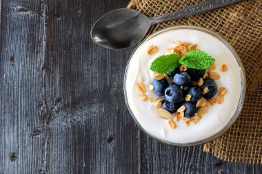 Yoğurt tatlı yaban mersini ve granola, rustik koyu renkli ahşap görünümü yukarıda