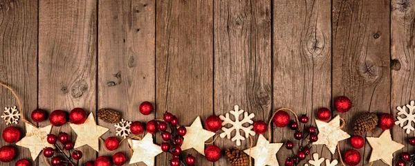 Christmas border banner with wood star ornaments and red baubles. Top view on an old wood background.
