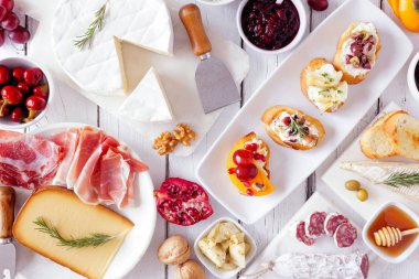 Çeşitli peynirler, etler ve crostini 'nin parti aperatifleri. Beyaz ahşap arka planda üst görünüm.