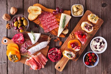 Çeşitli peynirler, etler ve crostini ile parti aperatifleri. Kırsal ahşap arka planda üst görünüm.