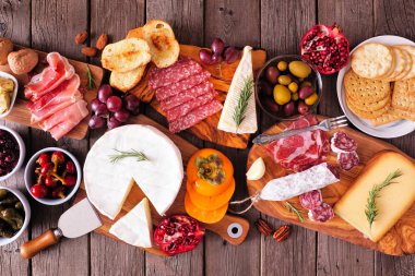 Etler, peynirler ve aperatiflerden oluşan Charcuterie panoları. Kırsal ahşap arkaplanda en iyi görünüm tablosu.