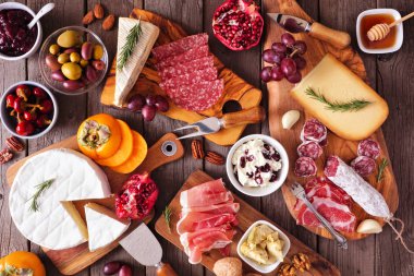 Çeşit çeşit peynir, et ve aperatiflerden oluşan Charcuterie panoları. Kırsal ahşap arka planda masa manzarasının üstünde.