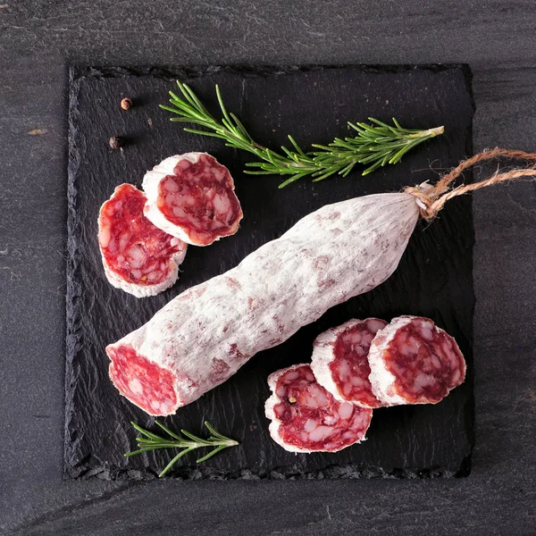 Traditional dry cured sausage. Top view, sliced on a slate serving board