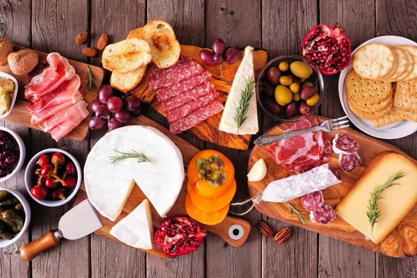 Etler, peynirler ve aperatiflerden oluşan Charcuterie panoları. Kırsal ahşap arkaplanda en iyi görünüm tablosu.