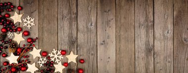 Noel köşesi afişi, ahşap yıldız süslemeleri ve kırmızı takılarla. Eski bir ahşap arka planda manzaranın üstünde.