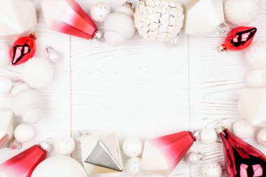 Modern kırmızı ve beyaz süslemelerden oluşan bir Noel çerçevesi. Beyaz ahşap zemin üzerinde görünüm.