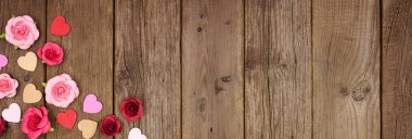 Ahşap kalpler ve kağıt güllerden oluşan köşeli Sevgililer Günü afişi kopyalanmış ahşap bir arka plana karşı