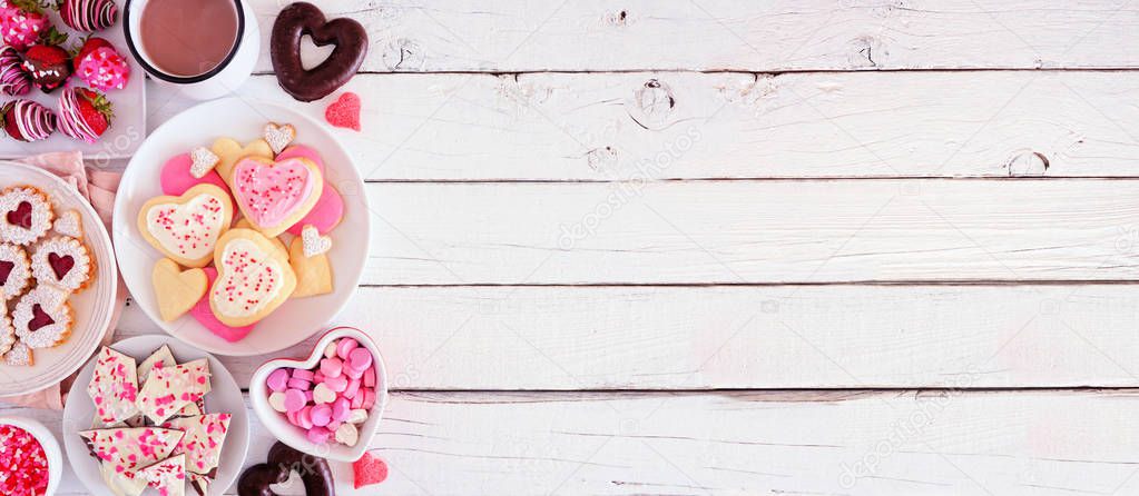 Valentines Day banner with side border of various sweets and cookies. Top view over a white wood background. Love and hearts theme. Copy space.