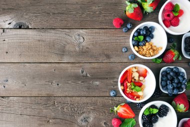 Çeşit çeşit böğürtlen ve tahıl gevreğiyle sağlıklı yoğurt kaseleri. Üst sınır, ahşap bir arka plana karşı. Boşluğu kopyala.