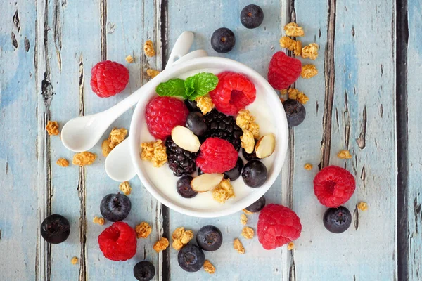 碗酸奶与健康新鲜的浆果和燕麦 近距离俯瞰乡村蓝木背景 — 图库照片