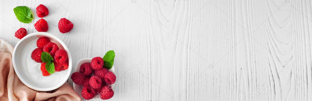 Healthy yogurt with raspberries. Banner with corner border against a rustic white wood background. Copy space.