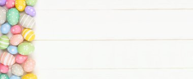 Pastel renkli Paskalya Yumurtası afişi beyaz ahşap arka planda yan sınırı var. Kopyalama alanı olan üst görünüm.