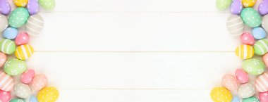 Pastel renkli Paskalya Yumurtası afişi beyaz ahşap arka planda çifte kenarı var. Kopyalama alanı olan üst görünüm.