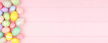 Pembe ahşap arka planda pastel renkli yumurta kenarlı Paskalya bayrağı. Kopyalama alanı ile genel görünüm.