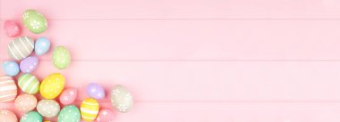 Pembe ahşap arka planda pastel renkli yumurta köşeli Paskalya bayrağı. Kopyalama alanı olan üst görünüm.