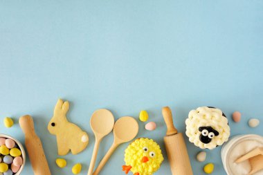 Paskalya tatlıları ve kurabiyeler. Üst görünüm alt kenarı, yumuşak mavi arkaplan üzerinde. Bahar tatili pişirme konsepti.