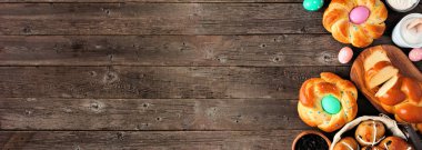 Paskalya masası sahnesinde taze ekmekler var. Karanlık ahşap arka planda yan kenarı olan üst manzara afişi. Bahar tatili pişirme konsepti.